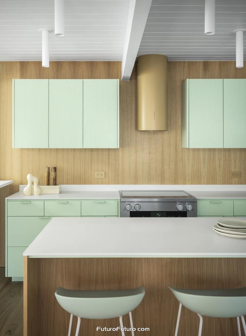 Gold Futuro Futuro 14 inch Jupiter cylindrical island range hood above a stainless range in a Palo Alto kitchen with mint green fluted cabinets, vertical wood paneling, and matching mint island stools.