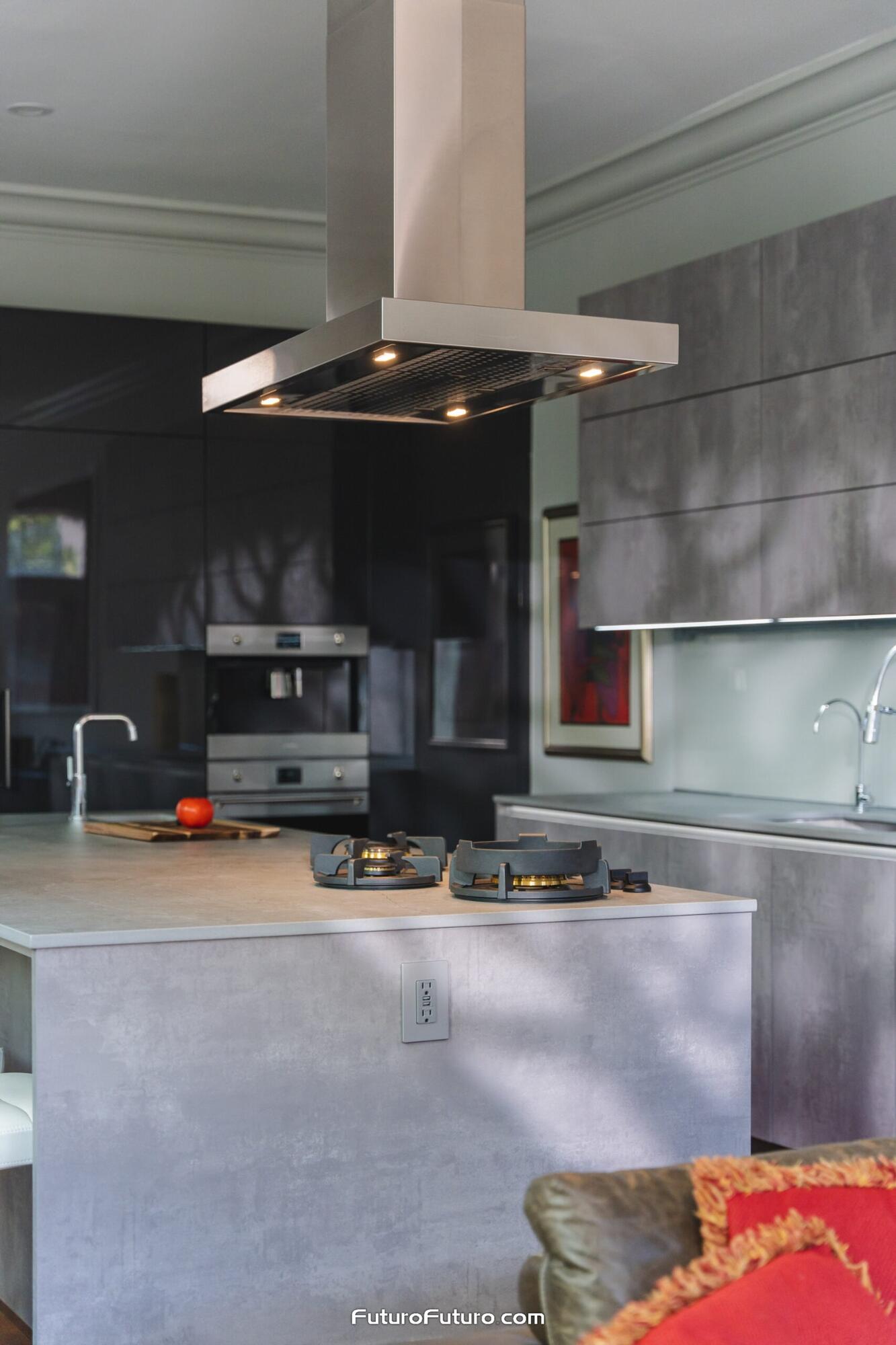 Stainless steel Futuro Futuro 36 inch Positano island range hood over a gray cooktop island in a Georgetown DC kitchen with dark and light gray cabinets, double ovens, canopy lights, and open living space beyond.